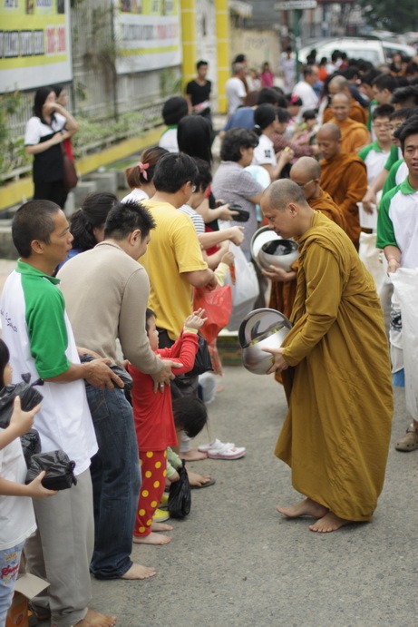 Alms giving to a Buddhist monk by a kid.